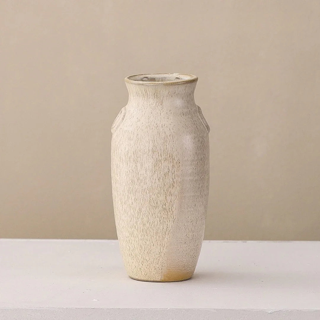 Minimalist beige ceramic vase with textured matte finish on a light surface