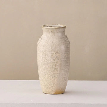 Minimalist beige ceramic vase with textured matte finish on a light surface