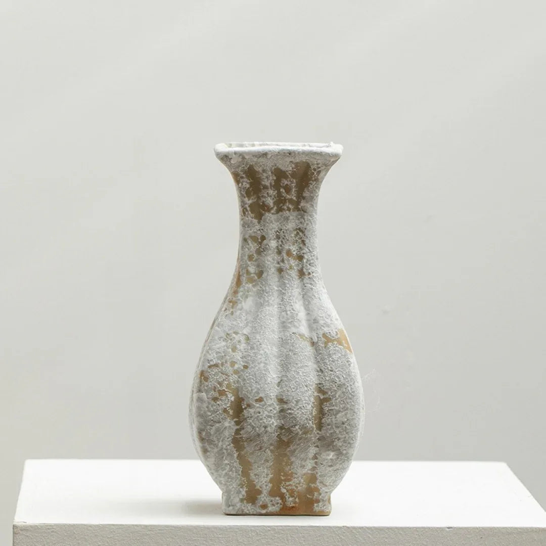 Textured ceramic vase with a narrow neck and abstract white and beige pattern on a plain background