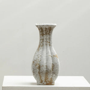 Textured ceramic vase with a narrow neck and abstract white and beige pattern on a plain background
