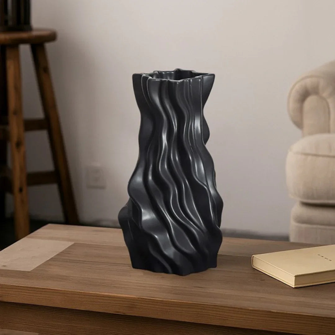 Modern black wavy ceramic vase on wooden coffee table in minimalist living room