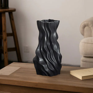 Modern black wavy ceramic vase on wooden coffee table in minimalist living room