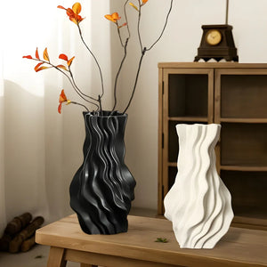 Modern black and white wavy ceramic vases on wooden table, home decor with dried flowers