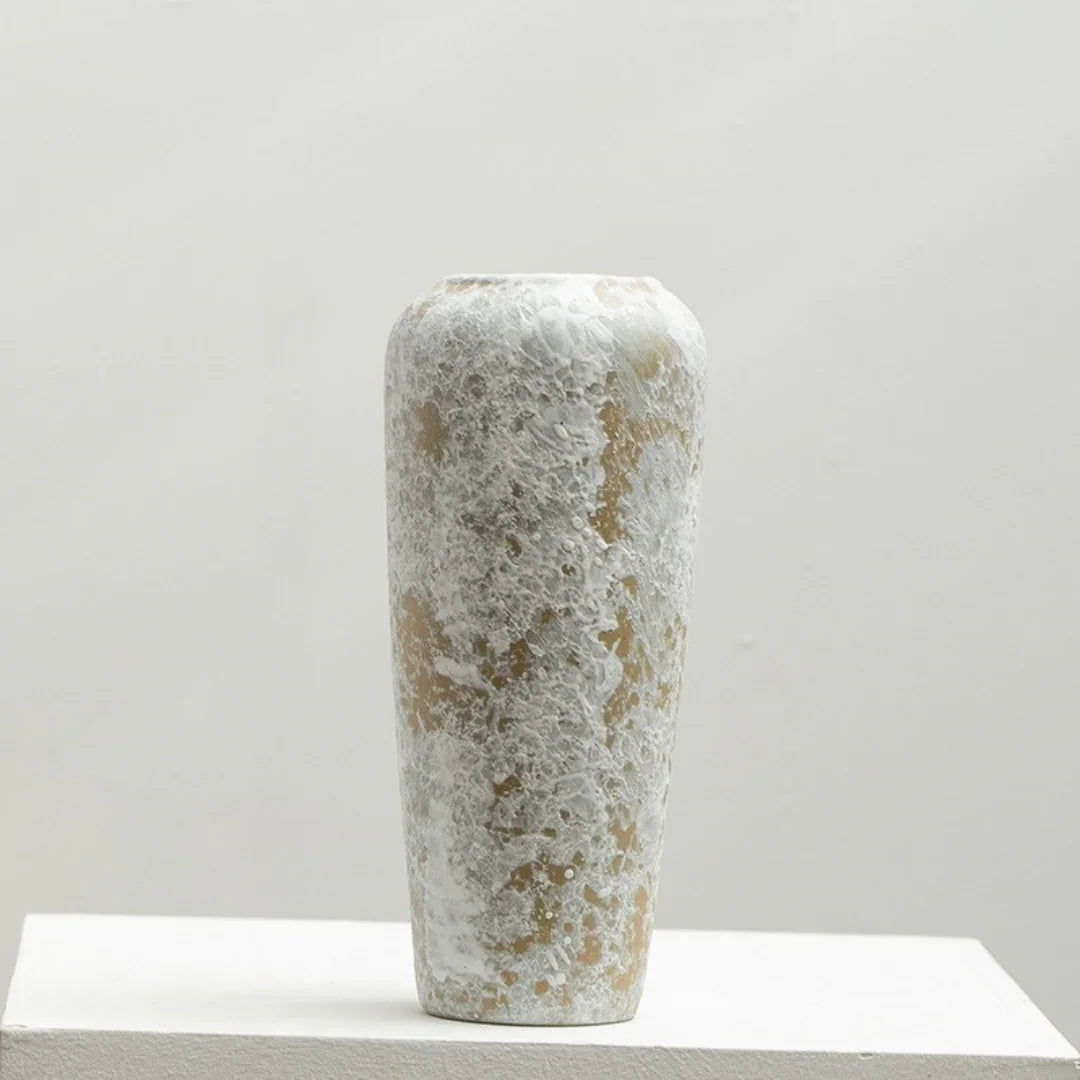 Tall ceramic vase with textured white and beige speckled finish on a light background