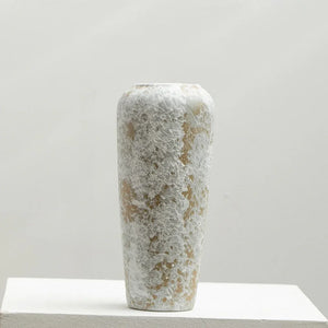 Tall ceramic vase with textured white and beige speckled finish on a light background