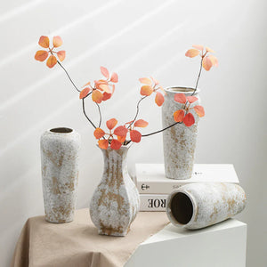 Rustic ceramic vases with orange autumn branches on a beige table in modern decor