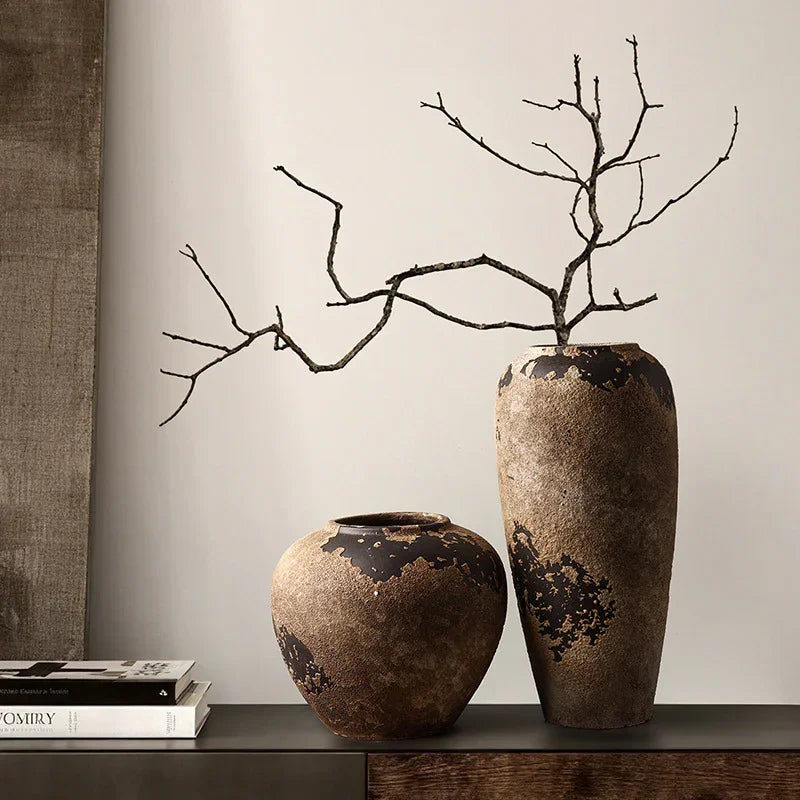 Two rustic ceramic vases with a dry branch on a modern console table