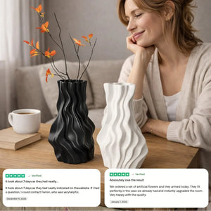 Woman smiling at black and white modern wavy vases with artificial orange flowers on wooden table.